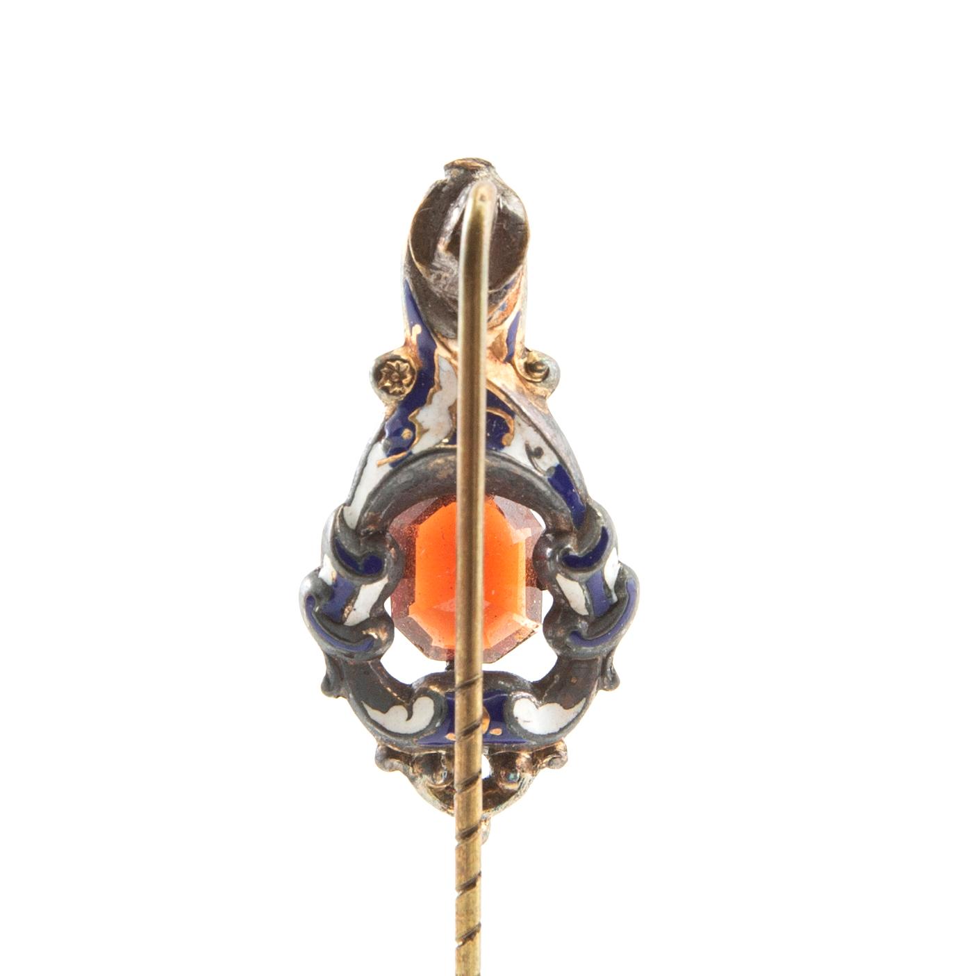 Kravattnål av förgylld mässing med dekor av emalj och en fasetterad granat, 1800-talets andra hälft.